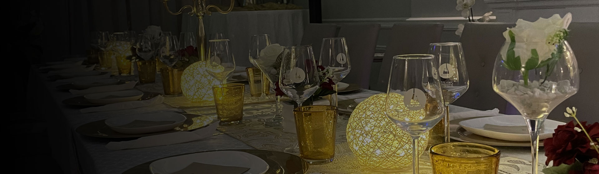 Tavola elegantemente apparecchiata con bicchieri di vetro e decorazioni luminose, creando un'atmosfera accogliente e raffinata.