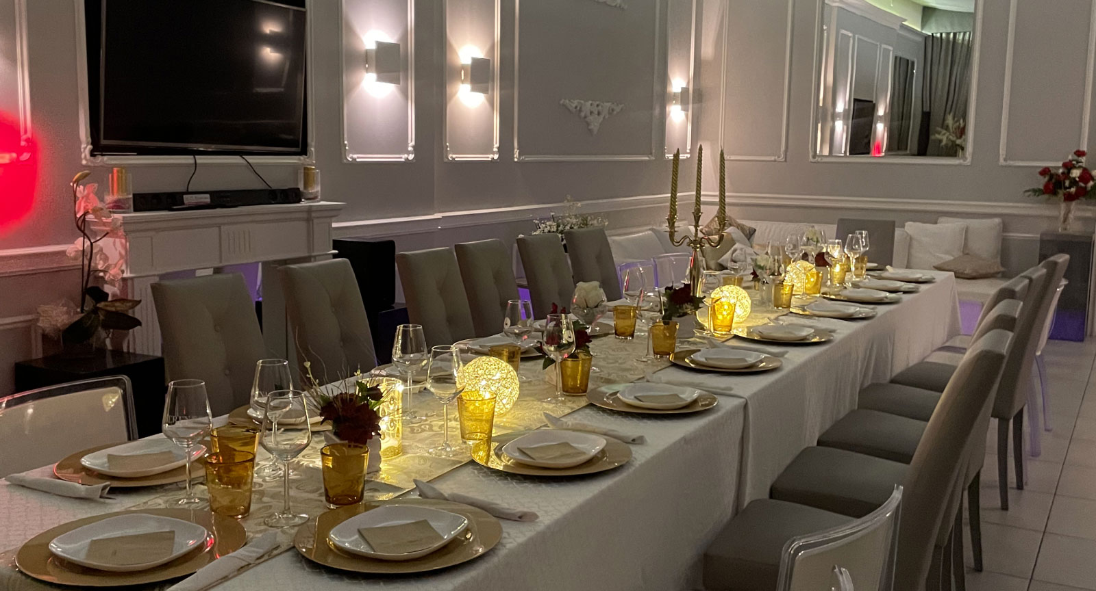 Una elegante tavolata imbandita con posate e bicchieri, decorata con candelabri e luci calde, pronta per una cena speciale.
