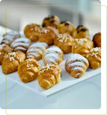 Vassoio di deliziosi croissant freschi, alcuni decorati con zucchero a velo e granelli di zucchero, appetitosi.