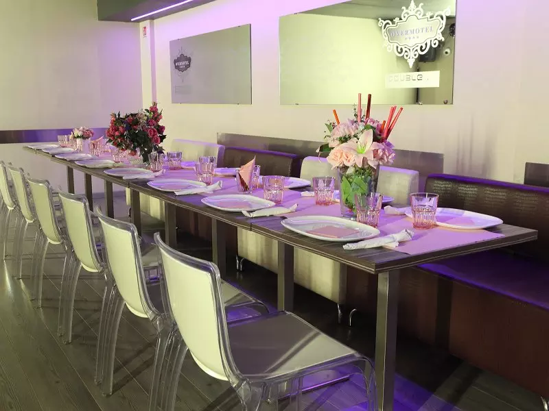 Immagine di un elegante tavolo da pranzo allestito con fiori freschi in vasi, piatti bianchi e bicchieri, in un ambiente moderno e luminoso.