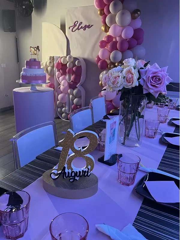 Decorazioni per una festa di compleanno con un tavolo elegantly apparecchiato, palloncini, fiori freschi e una torta.