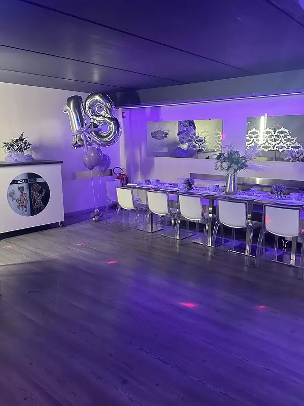 Una sala festiva decorata per un diciottesimo compleanno, con tavolo elegante, palloncini e luci colorate.