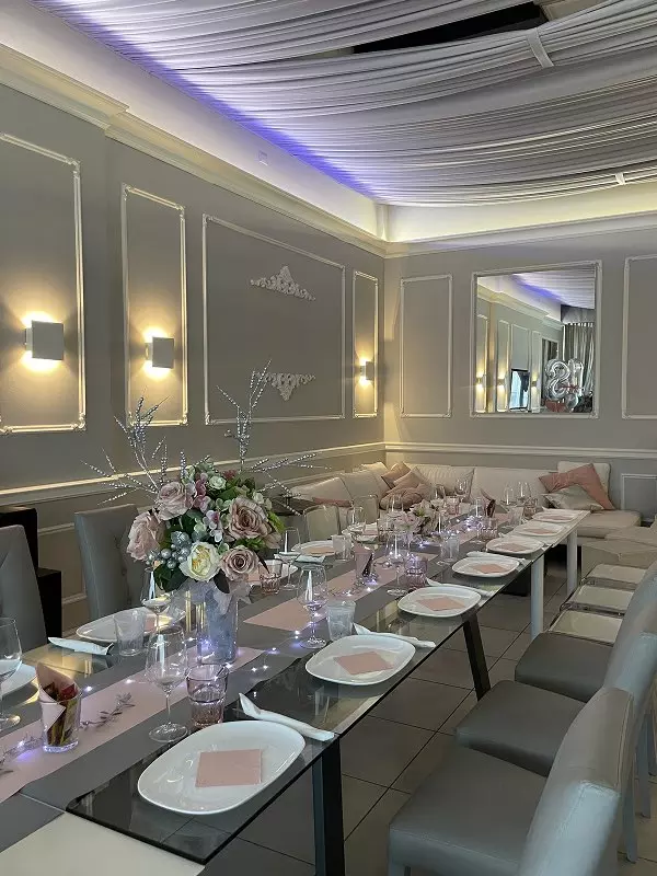 Setting elegante di una sala da pranzo decorata per un evento speciale, con tavolo imbandito e fiori freschi.