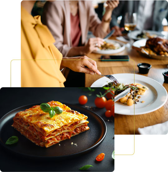 Un primo piano di una lasagna al forno servita su un piatto nero, circondata da pomodorini freschi. Sullo sfondo, persone gustano un pranzo in un ristorante, con piatti vari e una tavola ben apparecchiata.